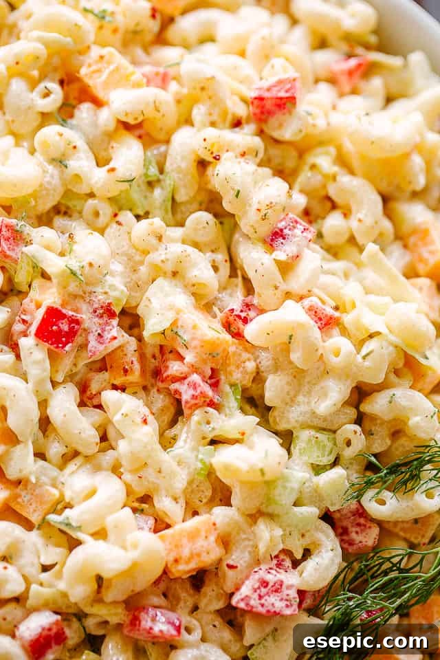 A close-up view of the creamy macaroni salad, highlighting its texture and the finely chopped vegetables, served in a clean white bowl.
