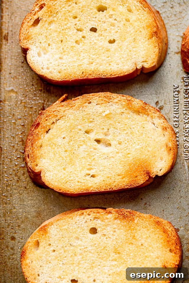 Golden-brown toasted garlic bread slices. Top view of perfectly golden-brown toasted Italian bread slices, brushed with olive oil and ready for garlic rubbing.