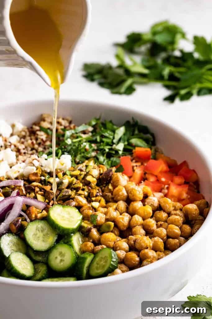Homemade dressing being poured over the freshly assembled Jennifer Aniston salad, enhancing its flavors and making it ready to serve.
