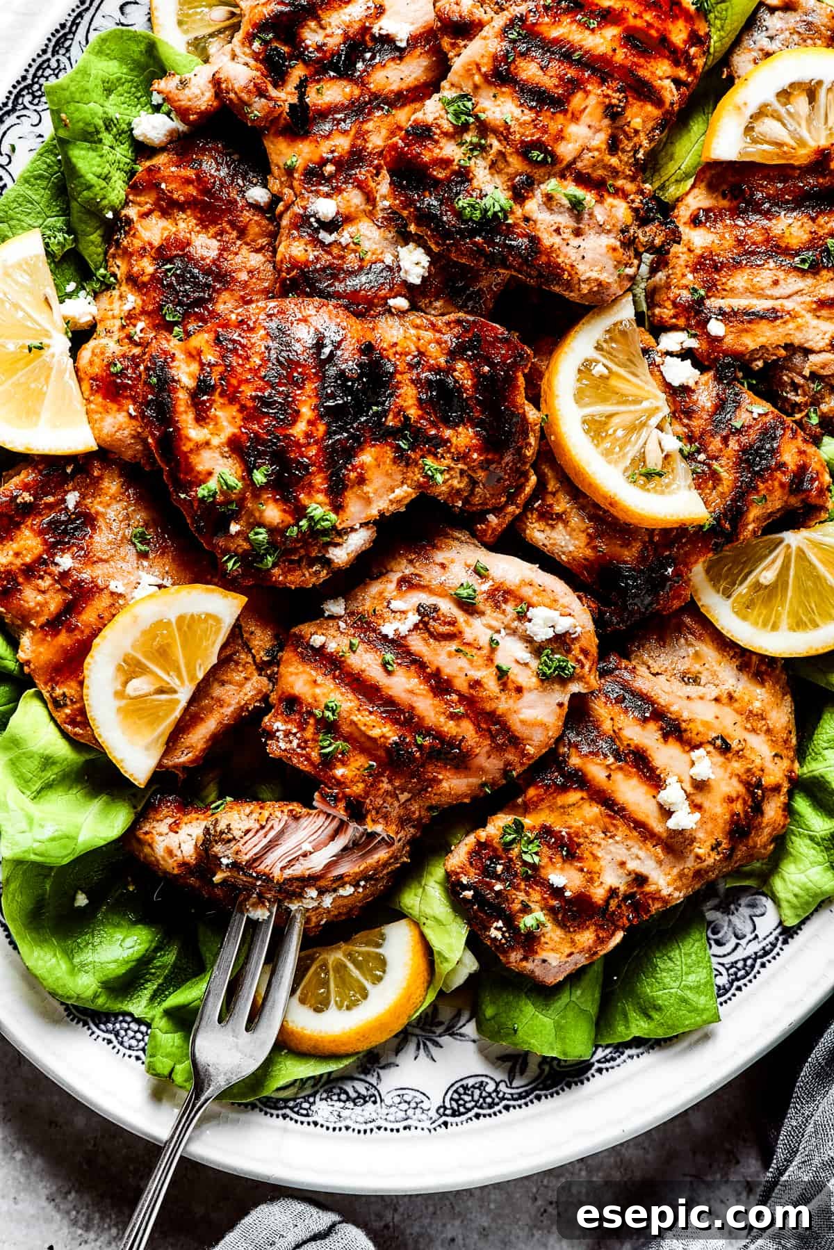 Yogurt Marinated Chicken is an easy grilled chicken recipe that’s versatile, zesty, and easy to make. Everyone will rave over this easy dish! Pulling a piece of grilled chicken apart with a fork.