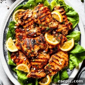 Grilled chicken thighs and lemon slices on a bed of salad greens.