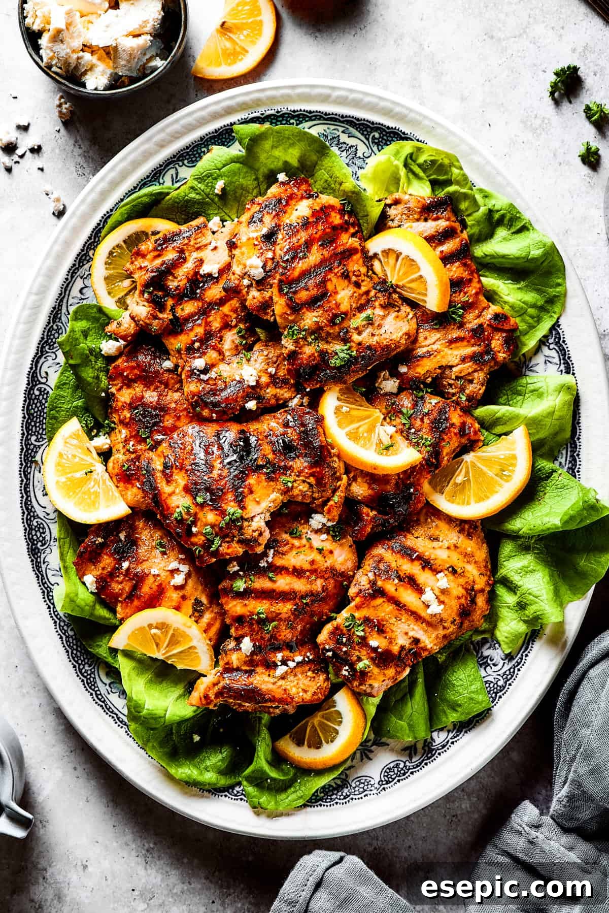 Luscious Yogurt Chicken 2 Grilled chicken thighs and lemon slices on a bed of salad greens.
