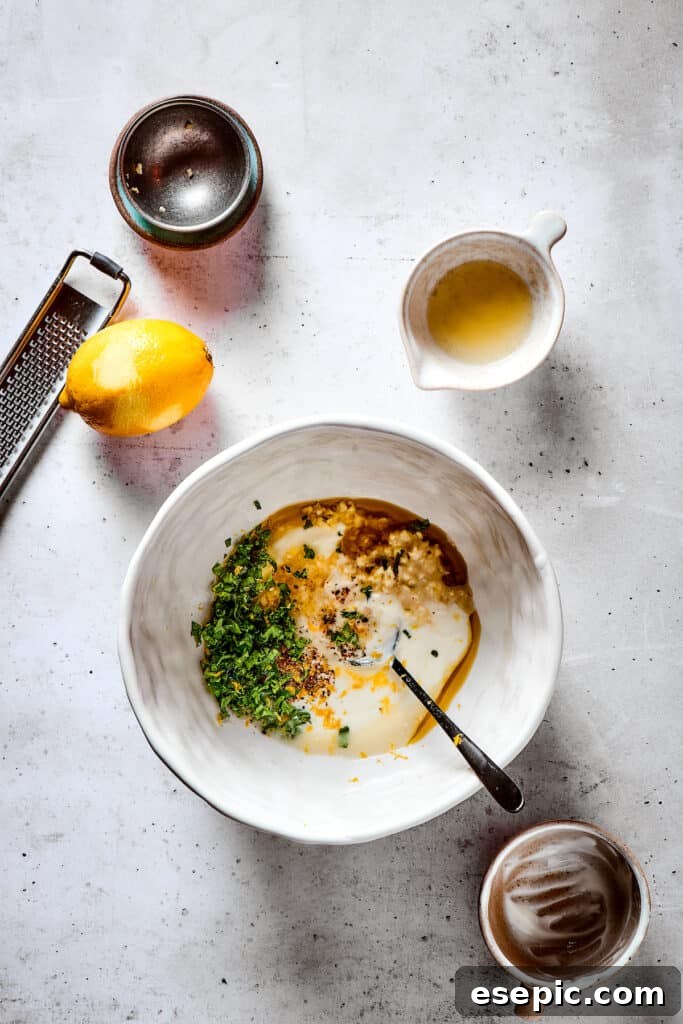 Yogurt Marinated Chicken is an easy grilled chicken recipe that’s versatile, zesty, and easy to make. Everyone will rave over this easy dish! Mixing marinade ingredients in a white bowl.