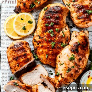 A sheet pan of lemon chicken with fresh herbs and lemon slices.