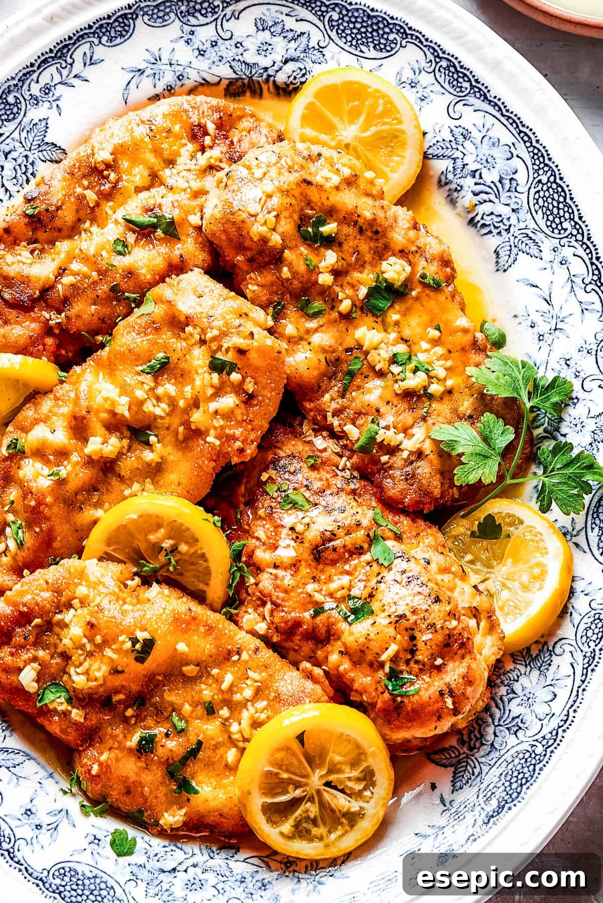 Homemade lemon chicken recipe arranged on a platter with parsley and lemon slices.