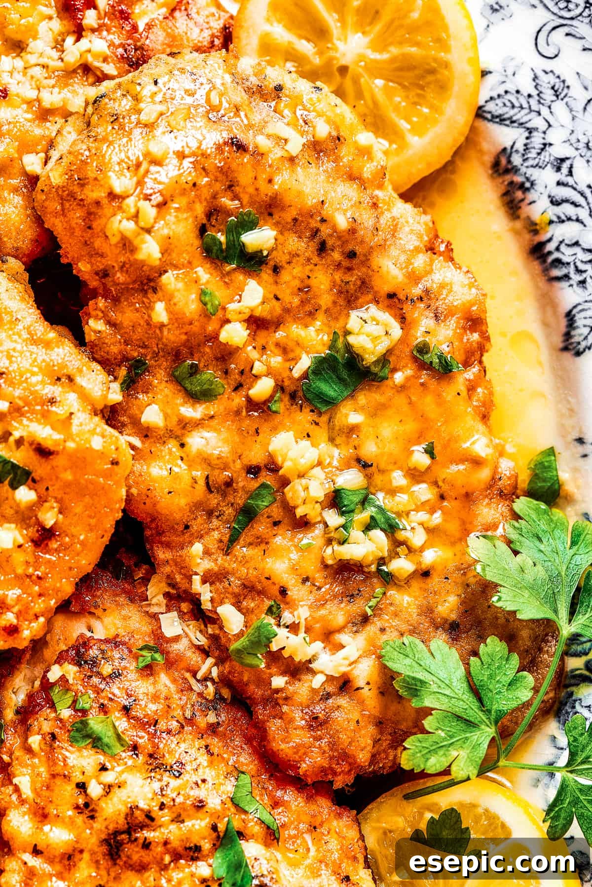 Close-up shot of lemon chicken breast on a platter, with garnishes of lemon.