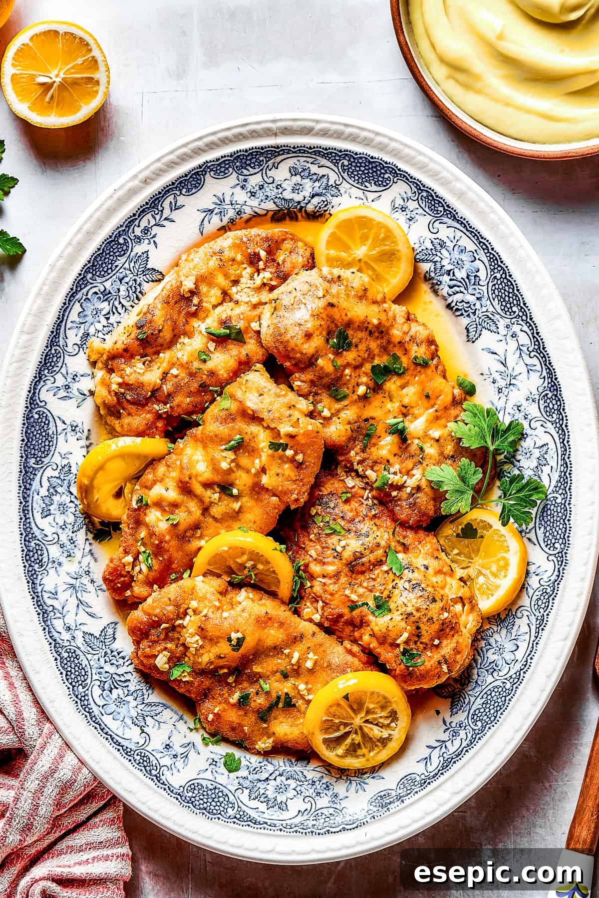 Lemon chicken breasts arranged on a blue oval plate.
