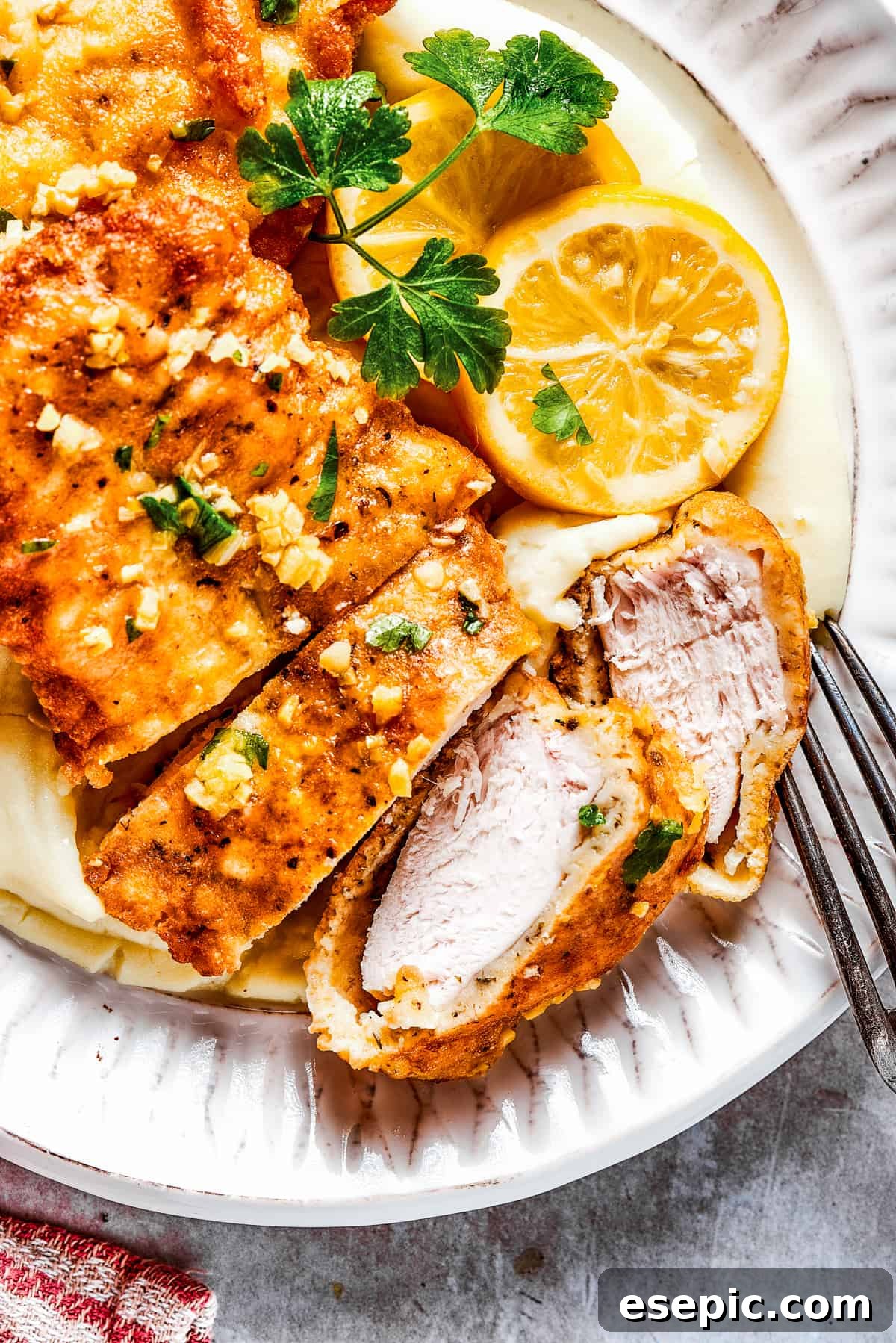 Sliced Breaded chicken with parsley and lemon slices placed next to it.