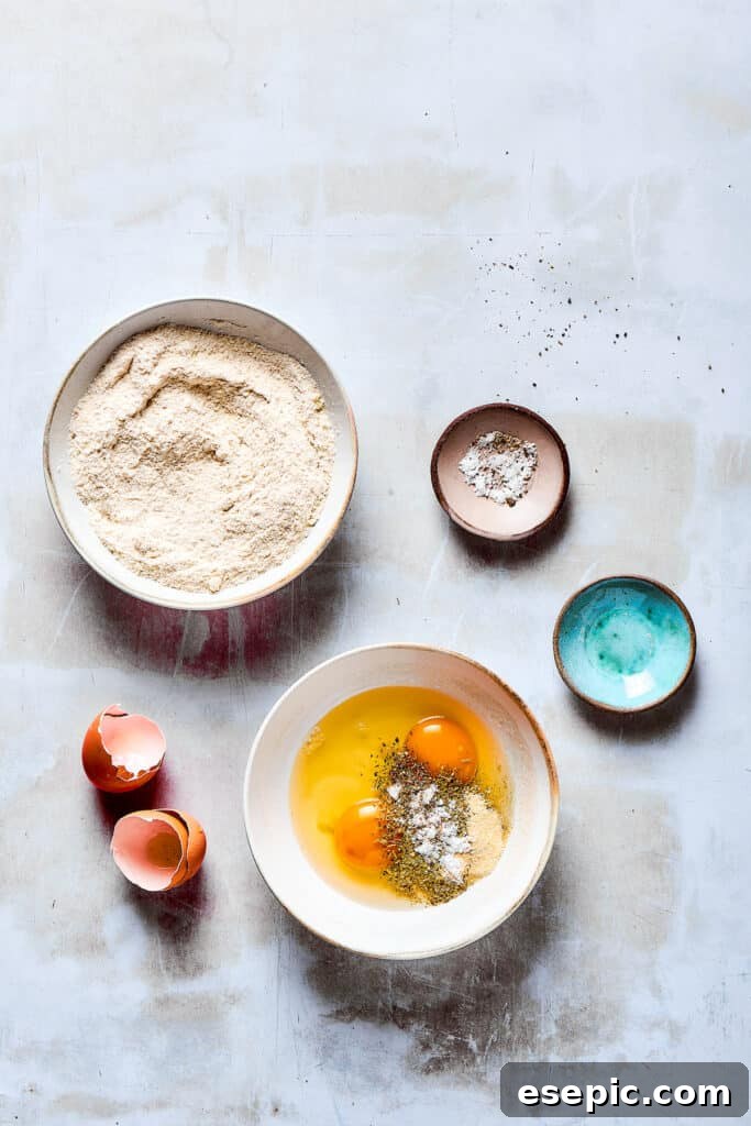 A bowl of breading ingredients next to a bowl of beaten eggs and seasonings.