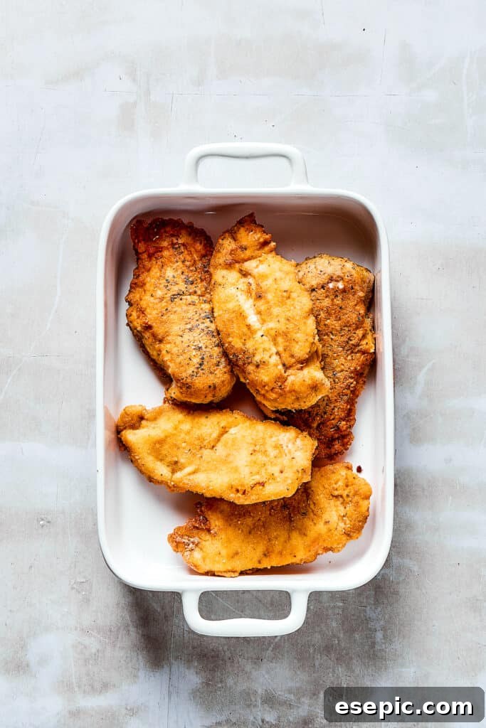 Breaded, browned chicken in a baking dish.