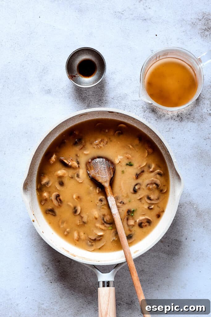 A close-up of the smooth, rich mushroom gravy simmering in a skillet, ready for the patties.