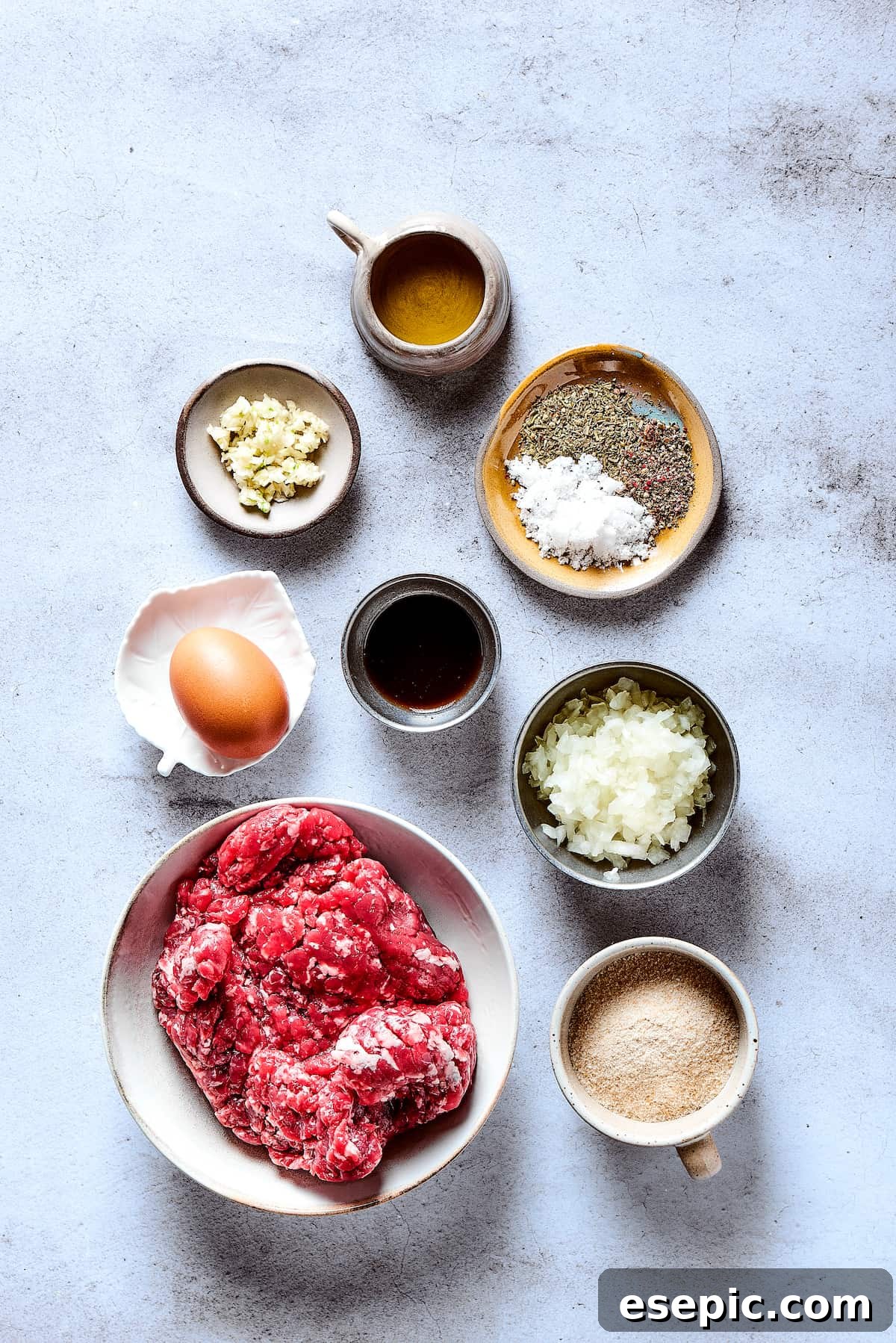 All the fresh ingredients for Salisbury steak, including ground beef, onions, mushrooms, and herbs, neatly arranged on a kitchen counter.