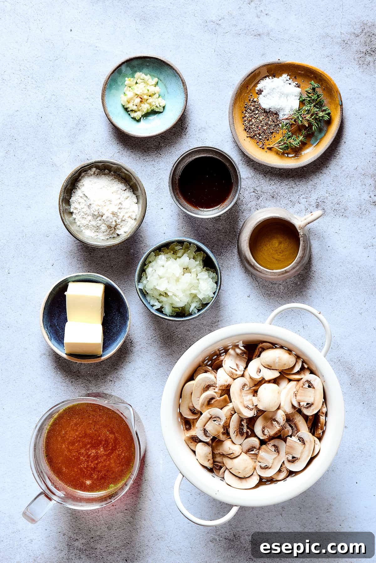 Ingredients for the mushroom gravy, including sliced mushrooms, onions, butter, and broth, laid out on a wooden surface.