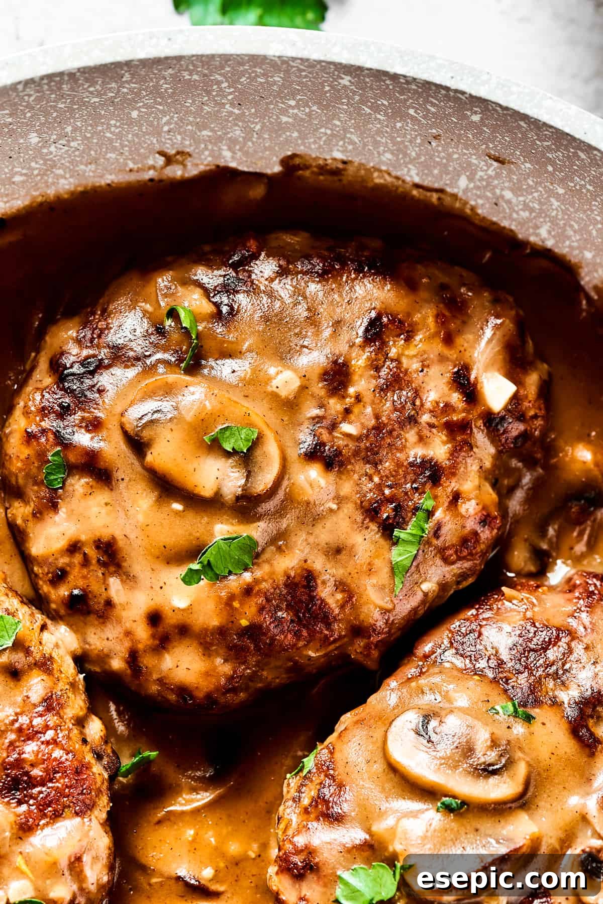 A perfectly cooked Salisbury steak covered with sliced mushrooms and rich brown gravy, ready to be enjoyed.