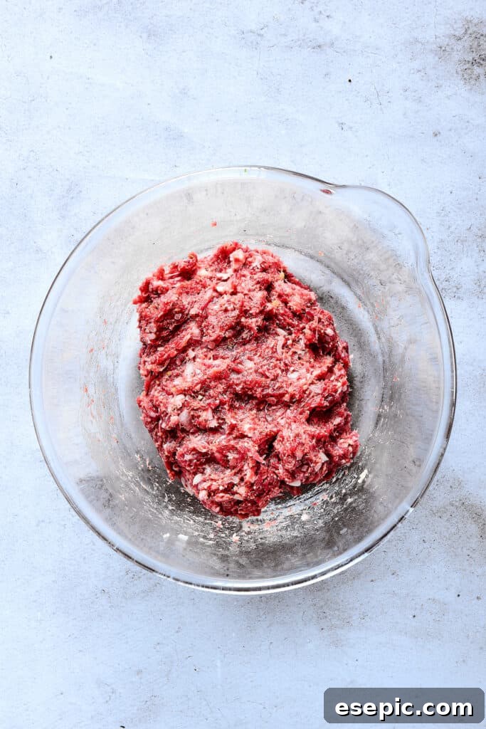 The ground beef mixture for Salisbury steak patties, perfectly combined in a glass bowl.