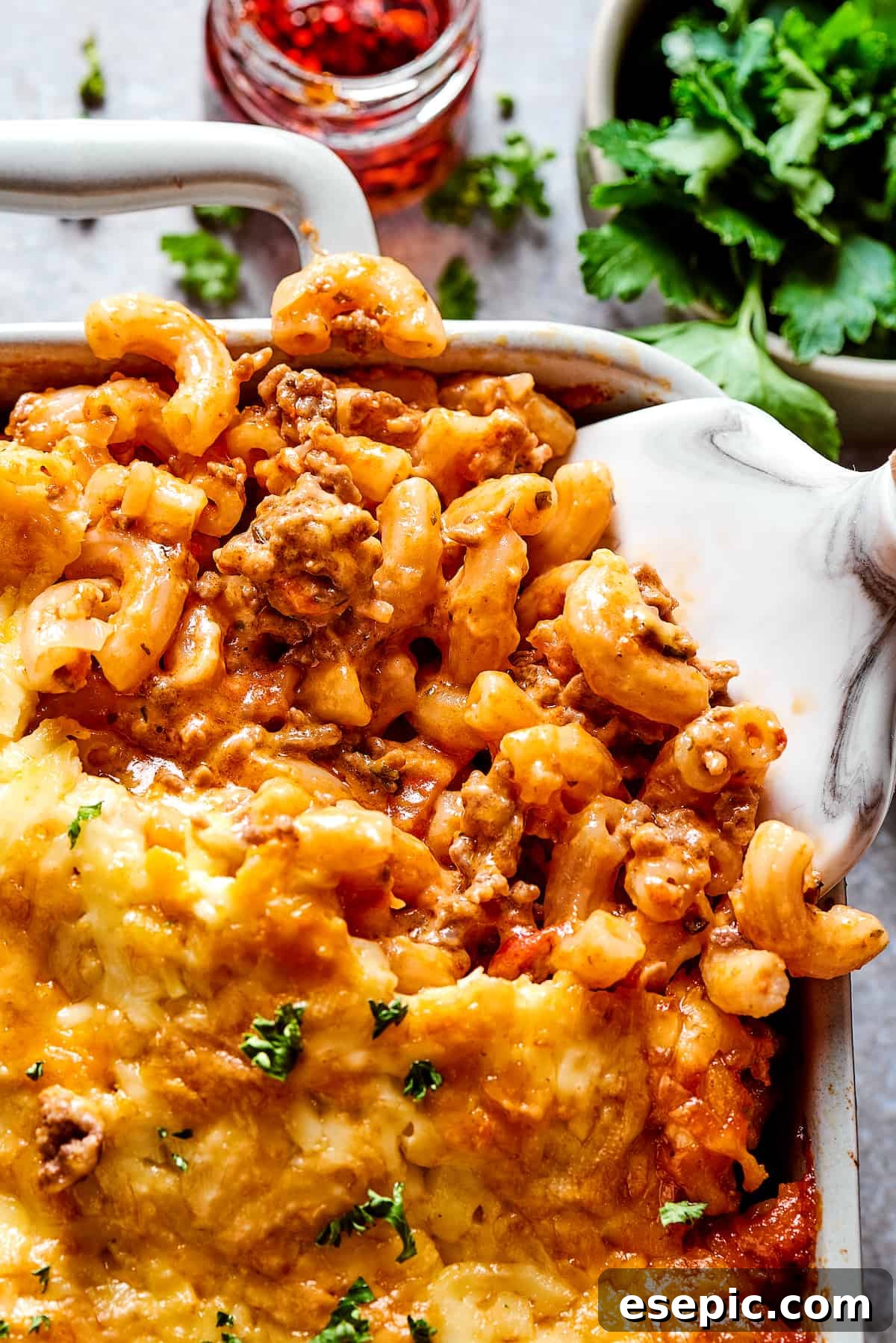 A generous portion of Cheesy Cheeseburger Casserole served from a large baking dish, showcasing the melted cheese and hearty ingredients.