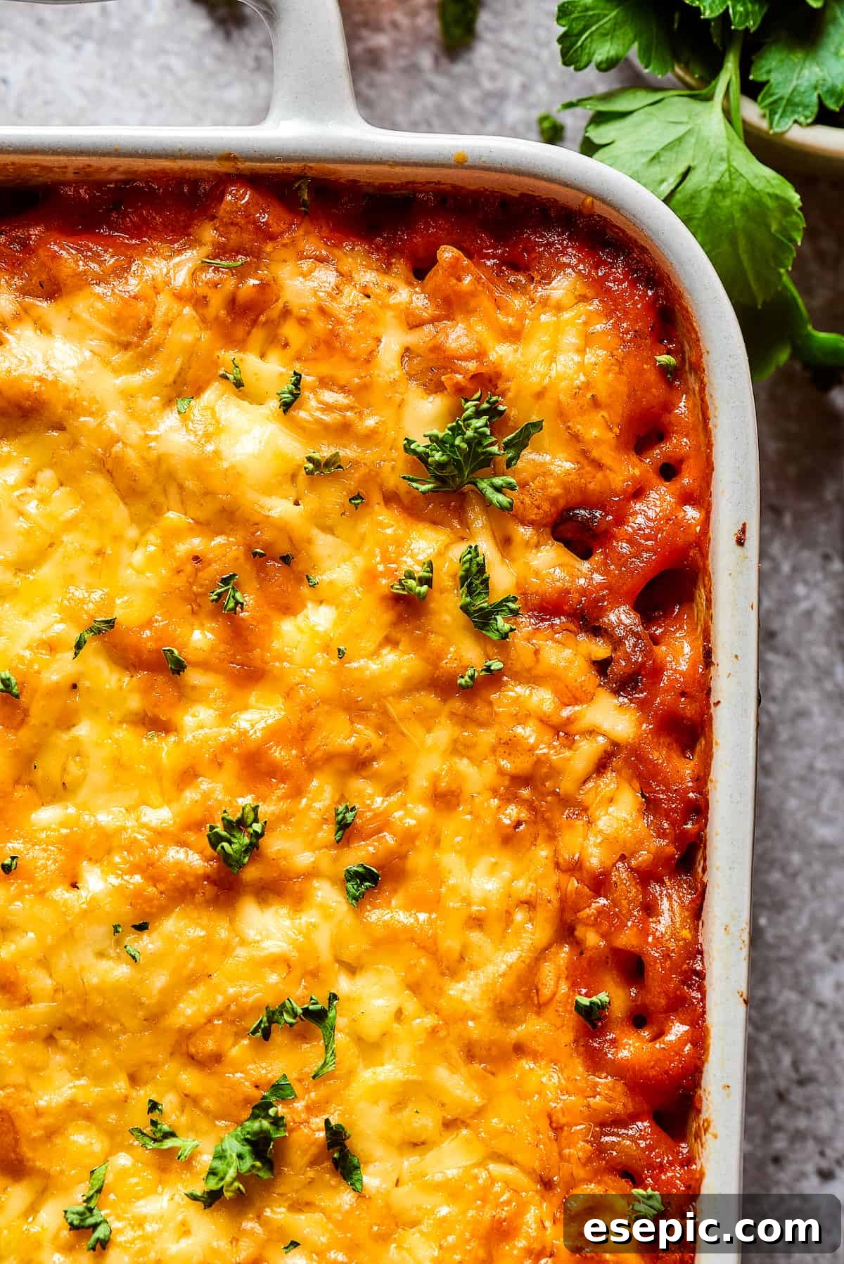 A close-up shot capturing the corner of a baked cheeseburger casserole, highlighting the bubbly, melted cheese and tender pasta.