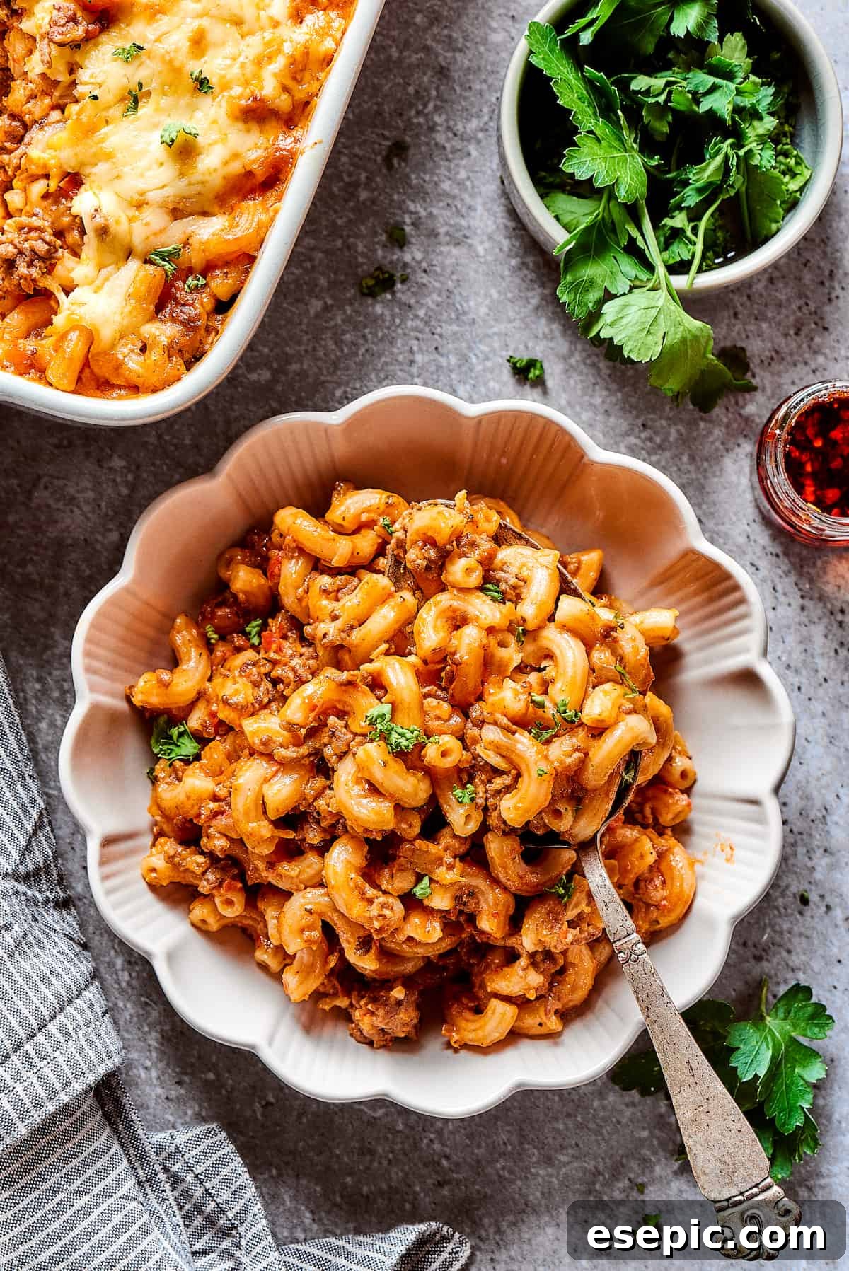 A perfectly portioned serving of cheeseburger casserole in an elegant bowl with fluted edges, ready to be enjoyed.