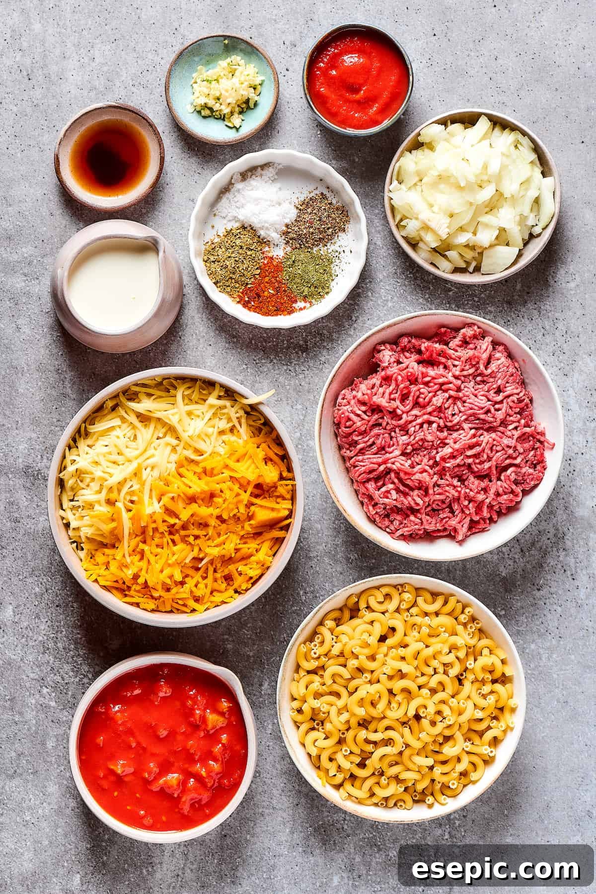 All the fresh and pantry ingredients for a delicious cheeseburger casserole, meticulously measured and arranged on a kitchen surface.