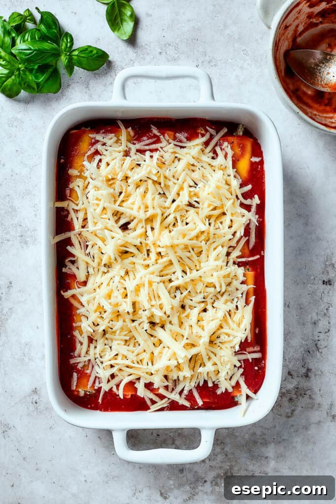 Pasta topped with sauce and shredded mozzarella in a baking dish.