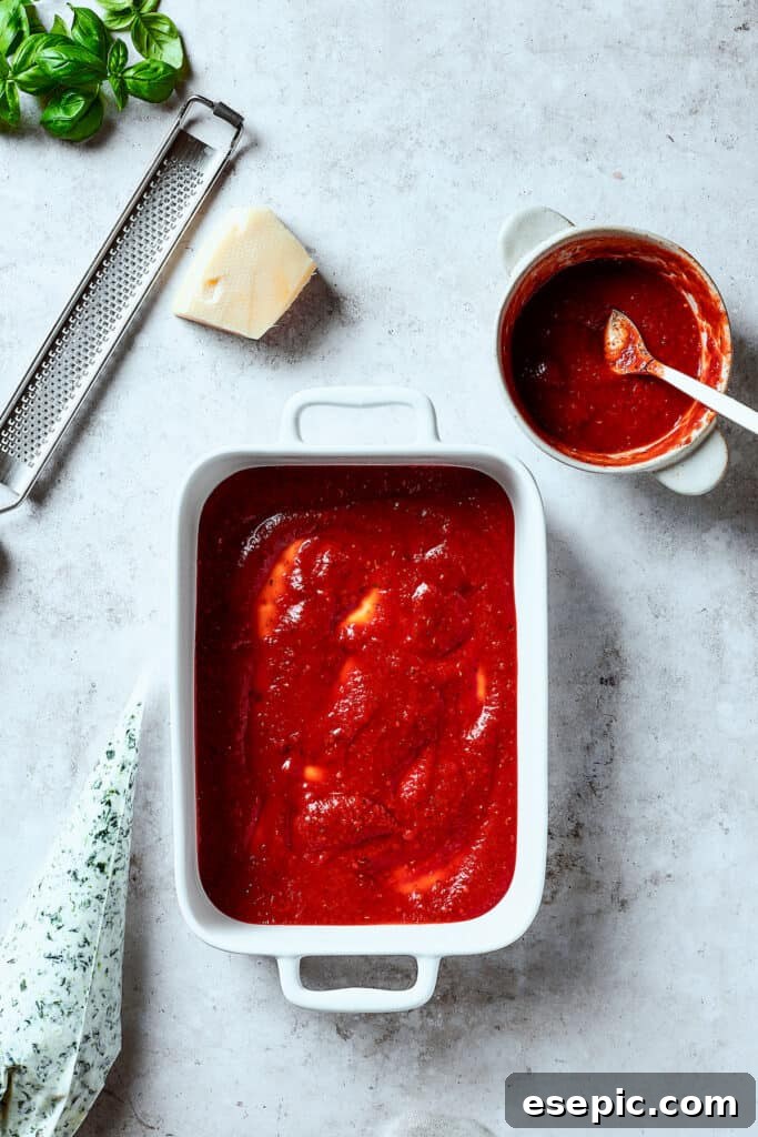 Red sauce spread into the bottom of a casserole.
