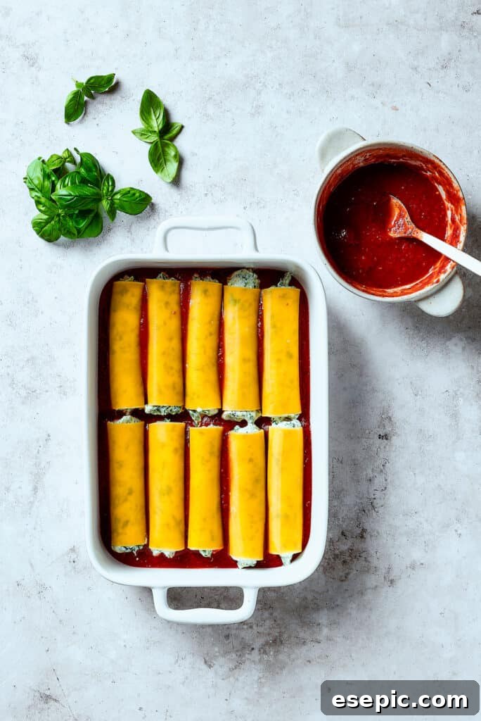 Stuffed manicotti pasta laid in a baking dish.