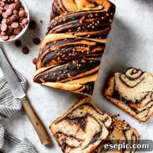 Decadent Chocolate Swirl Loaf 2 A loaf of chocolate babka that has been partially sliced. The slices are laid out on the work surface along with a bread knife and a dish of chocolate chips.