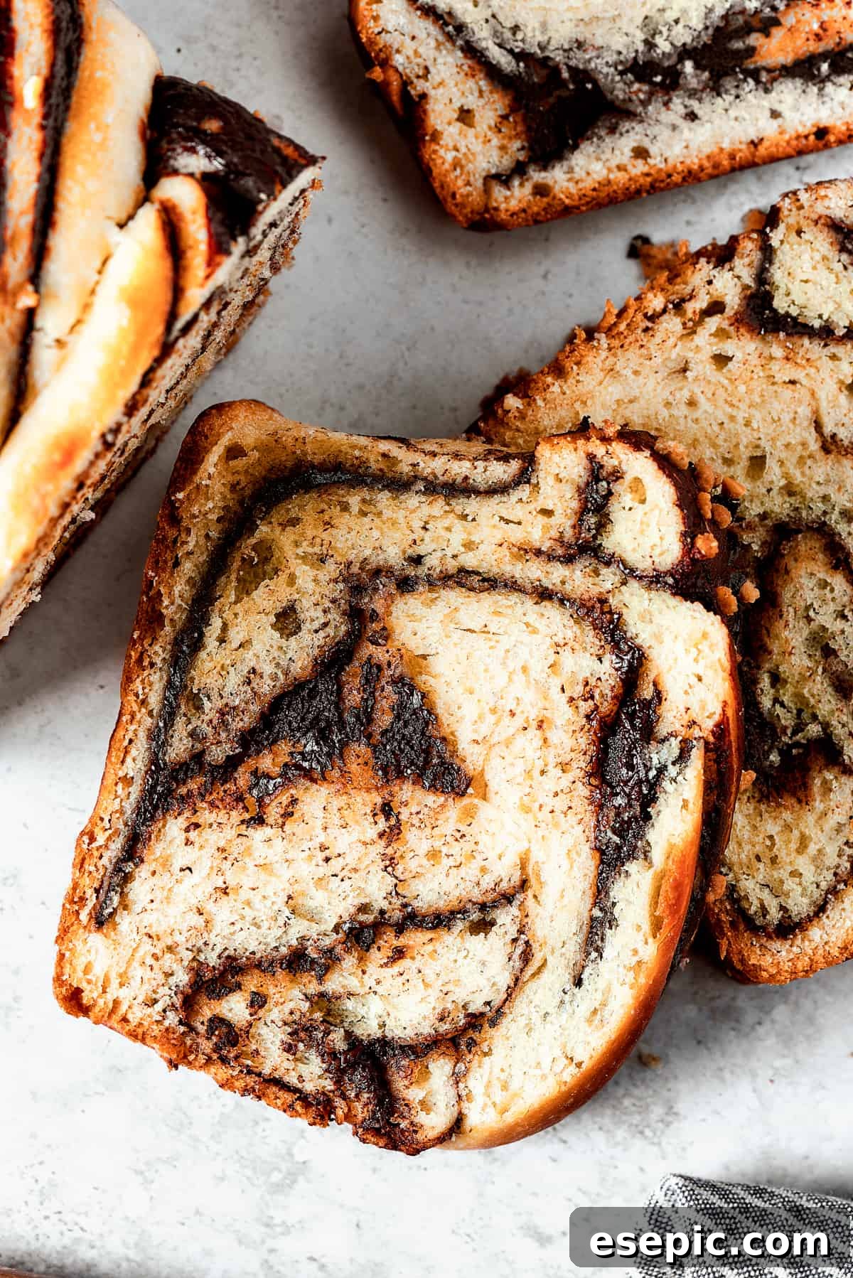 Sweet, puffy Chocolate Babka is an old-fashioned yeast bread swirled with layers of chocolate. Perfect for a special breakfast or dessert. Slices of chocolate babka on a work surface.