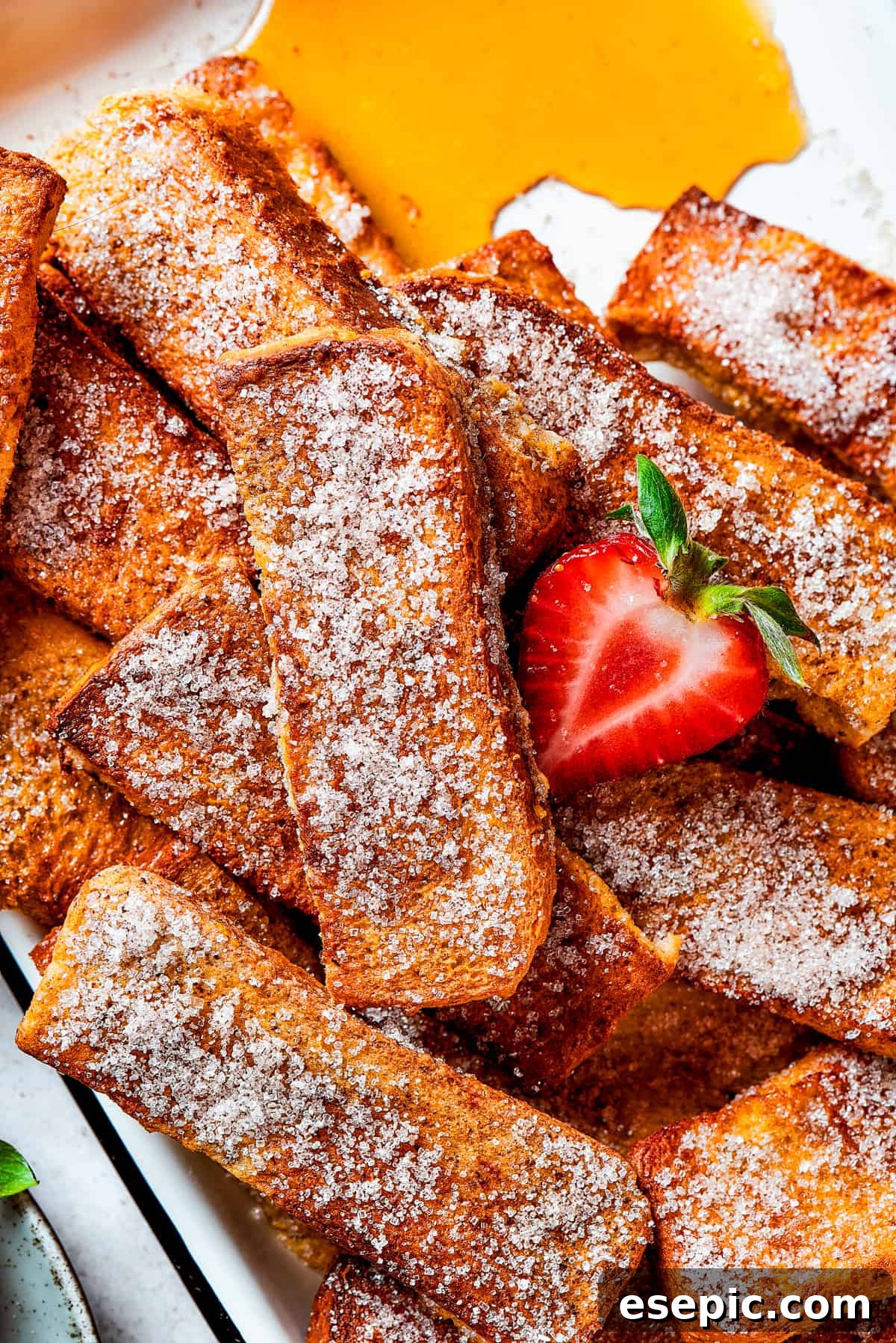 A shot of cinnamon-sugar-coated French toast sticks arranged on a white plate.