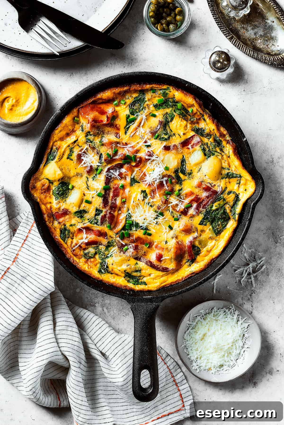 Spinach, Bacon, and Potato Frittata is a healthy, farmhouse-style dinner that's easy to make, and loaded with rich flavor. Perfect easy meal! A perfectly cooked, golden-brown frittata still in its cast-iron skillet, ready to be served.