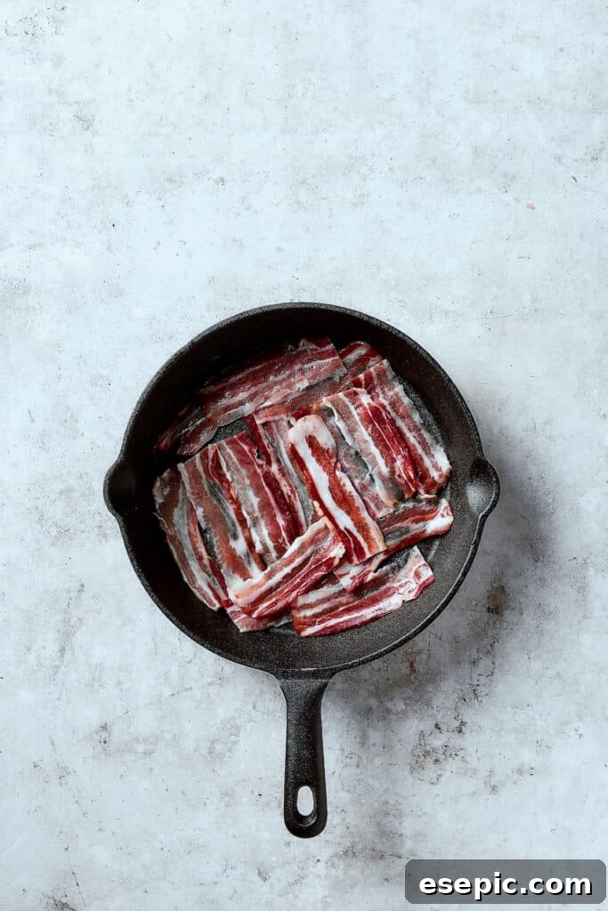 Spinach, Bacon, and Potato Frittata is a healthy, farmhouse-style dinner that's easy to make, and loaded with rich flavor. Perfect easy meal! Frying strips of bacon in a hot cast-iron skillet, creating crispy pieces for the frittata.