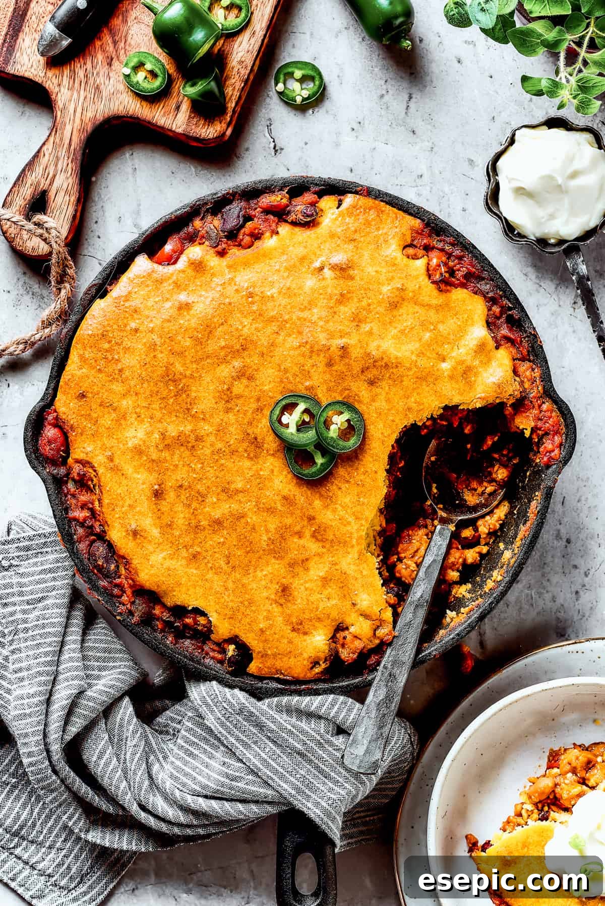 Chili cornbread casserole with a serving removed and a spoon resting in the skillet.