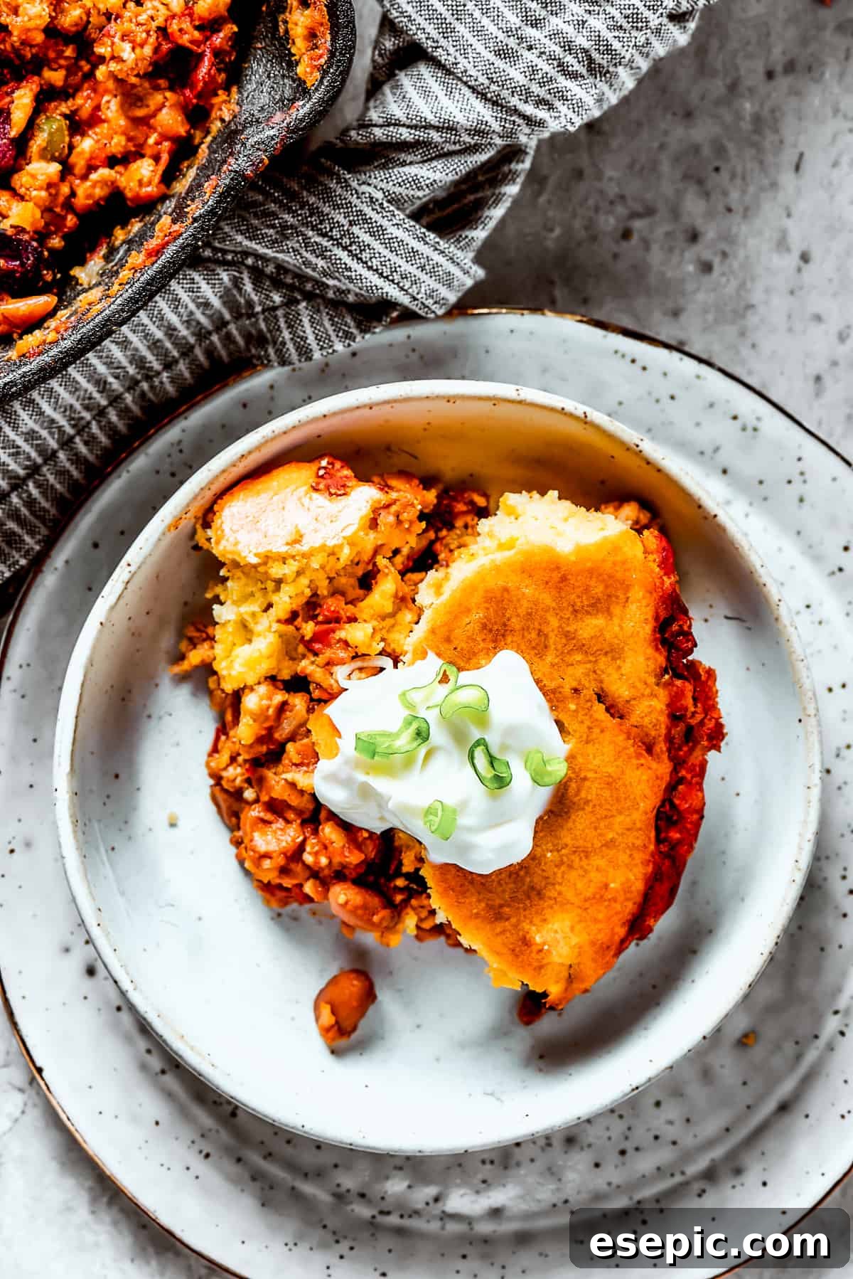 A serving of cornbread-topped turkey chili on an earthenware plate.
