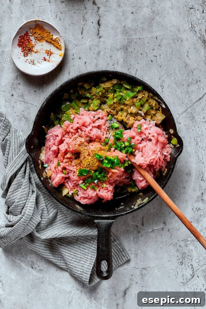 Ground turkey and other ingredients cooking in a skillet.