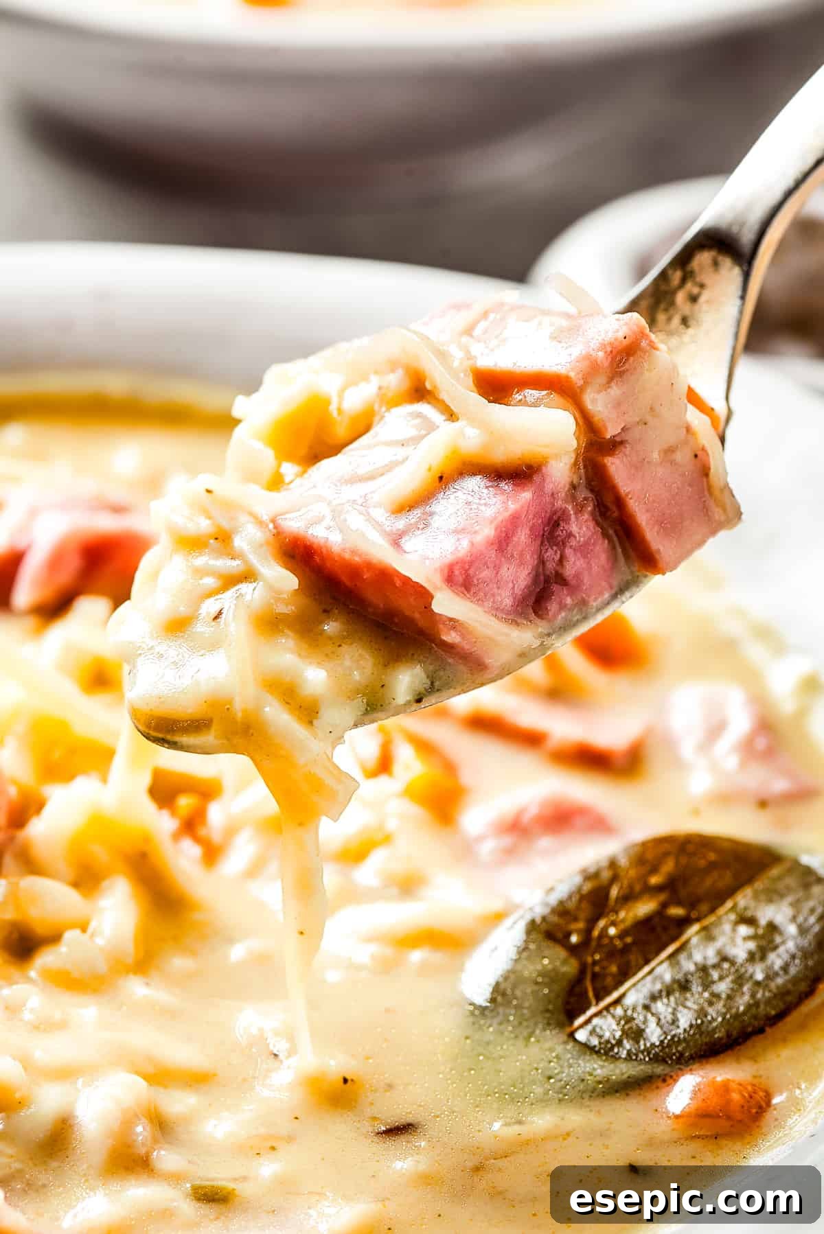 Reuben Comfort Bowl 13 A spoon lifting a portion of creamy Reuben soup out of a bowl, showing the rich texture and ingredients.
