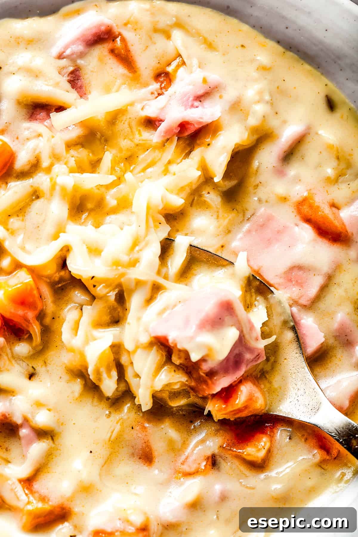 Reuben Comfort Bowl 3 Close-up shot of creamy Reuben Soup with melted Swiss cheese and a spoon ready to scoop.