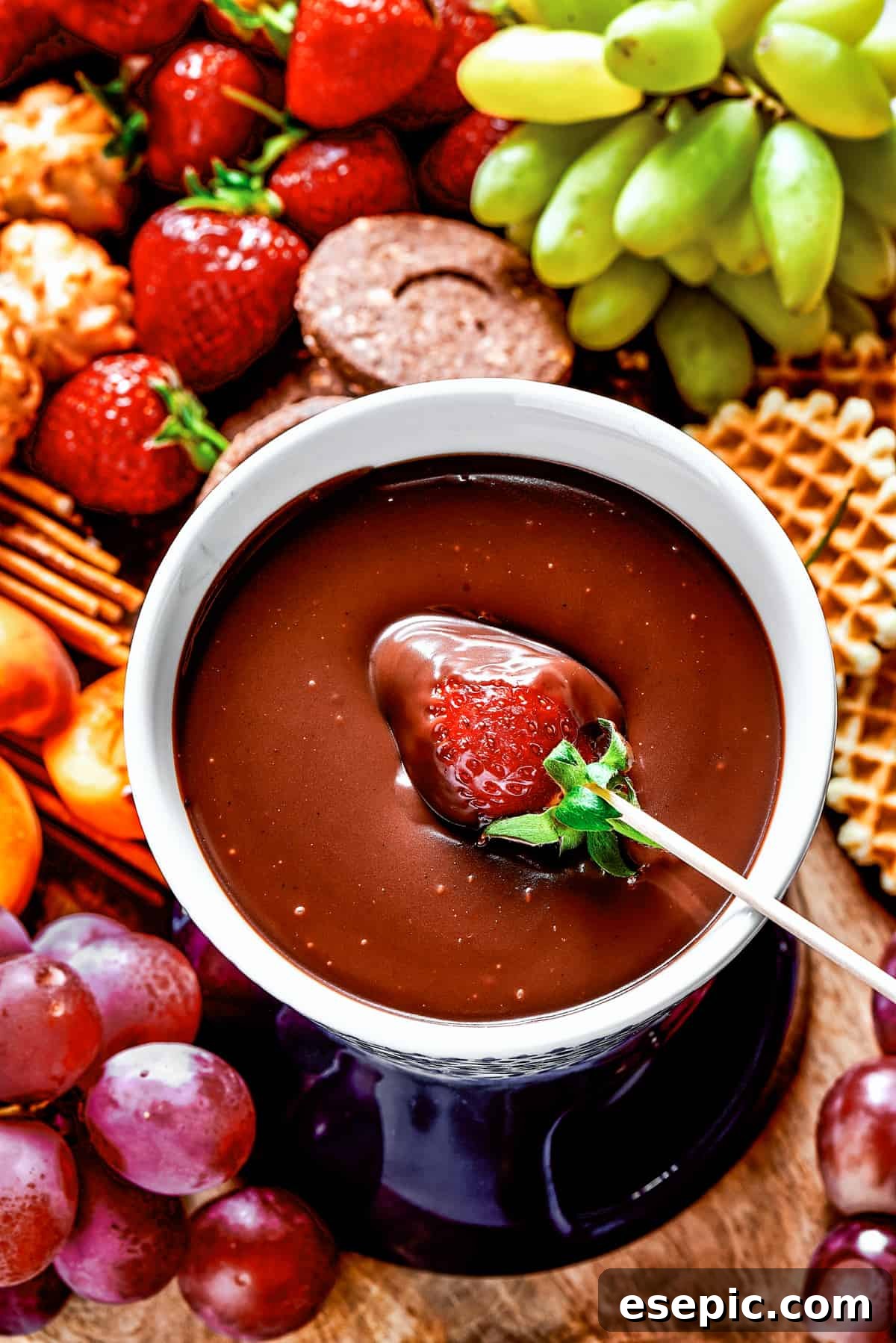 A fresh strawberry being dipped into a rich, warm chocolate fondue, highlighting its smooth texture.