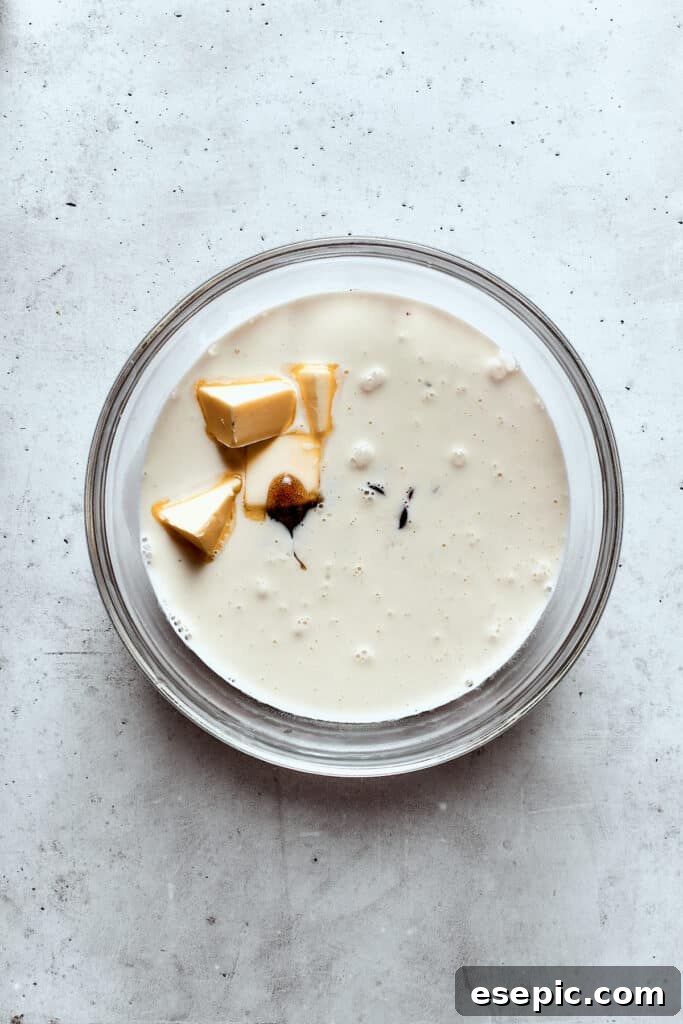 Adding pats of unsalted butter to the warm chocolate and cream mixture while gently stirring.