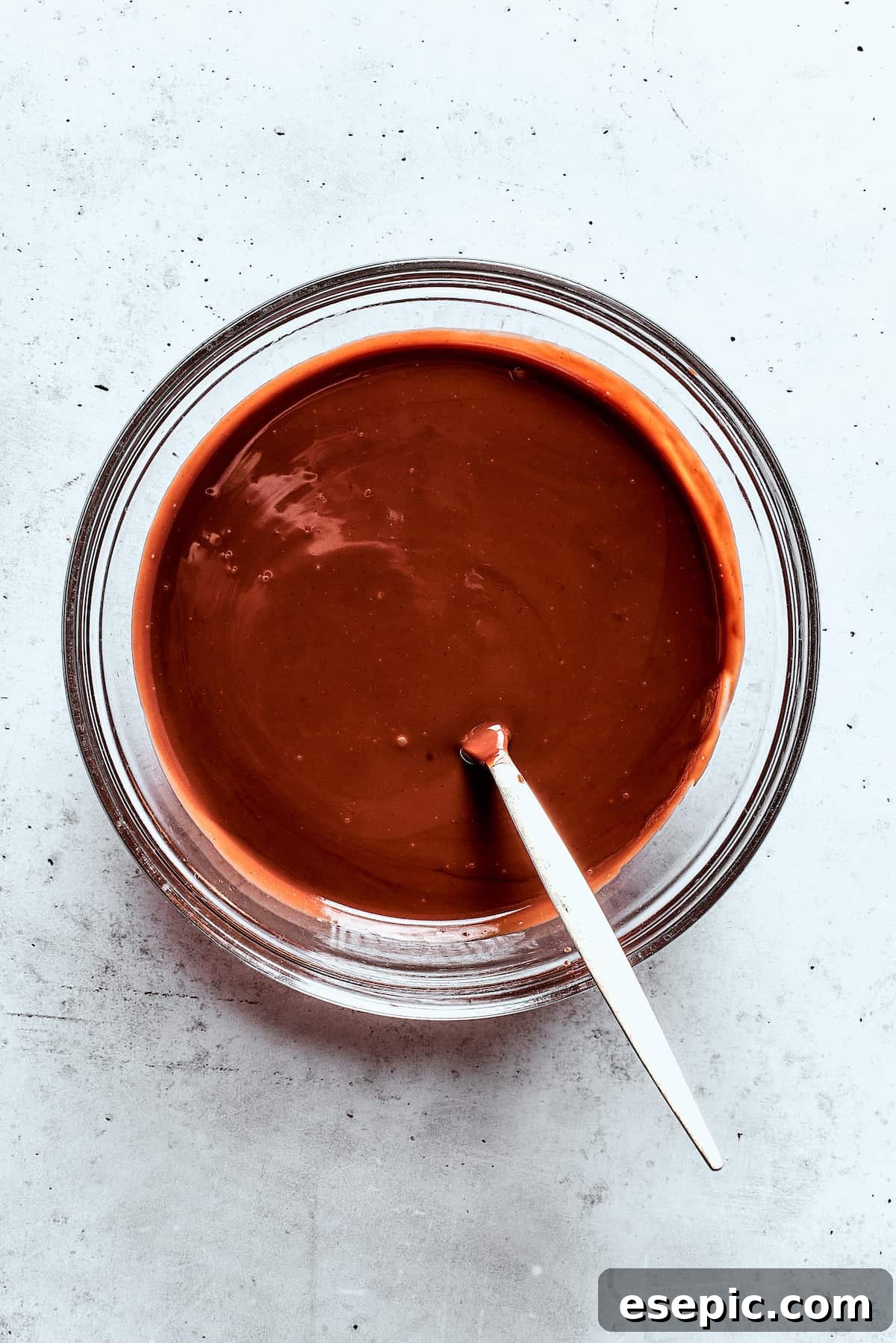 A close-up of a bowl filled with perfectly melted, glossy chocolate sauce, ready for dipping.
