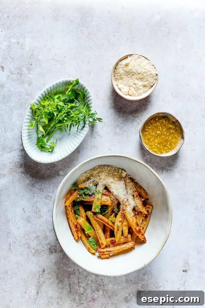 Baked fries in a bowl next to bowls of melted butter with garlic, parmesan, and parsley.