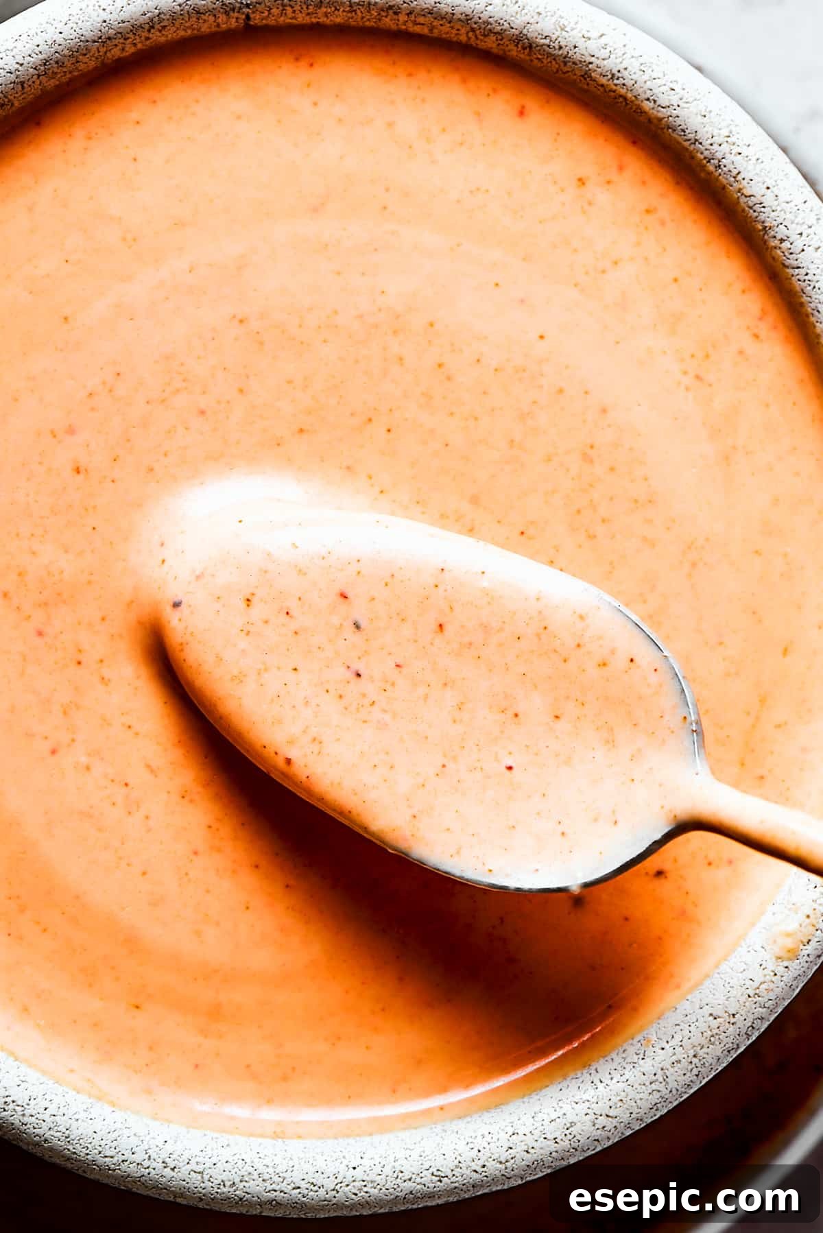 A close-up photo of freshly made homemade Yum Yum Sauce in a ceramic bowl, garnished with a sprinkle of paprika.