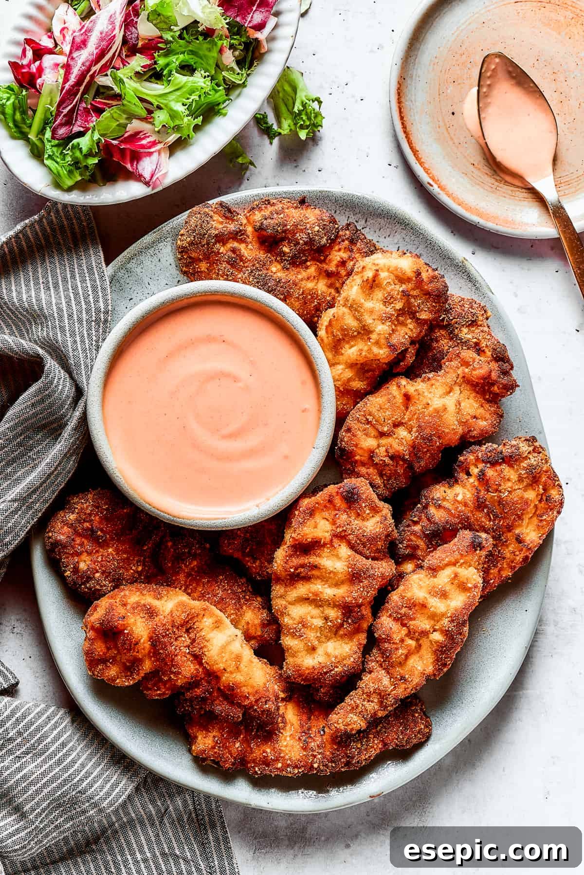 A vibrant platter of crispy chicken strips, perfectly golden, served with a side of creamy Yum Yum Sauce for dipping.
