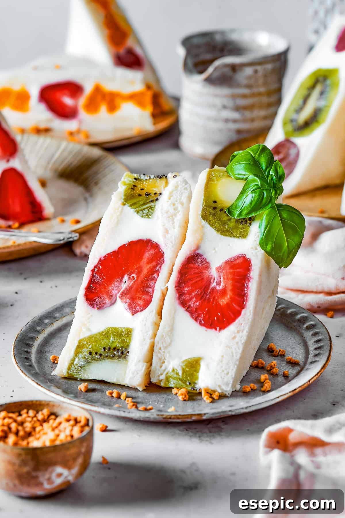 Close-up of a perfectly cut kiwi and strawberry fruit sando on a small plate, showing the clean cross-section.