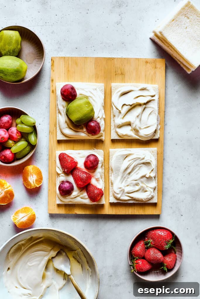 Carefully arranging colorful fresh fruit slices on whipped cream-covered white bread.