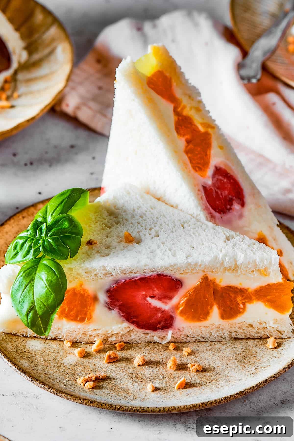 A vibrant Japanese Fruit Sando featuring fresh mandarin oranges and strawberries, cut diagonally.