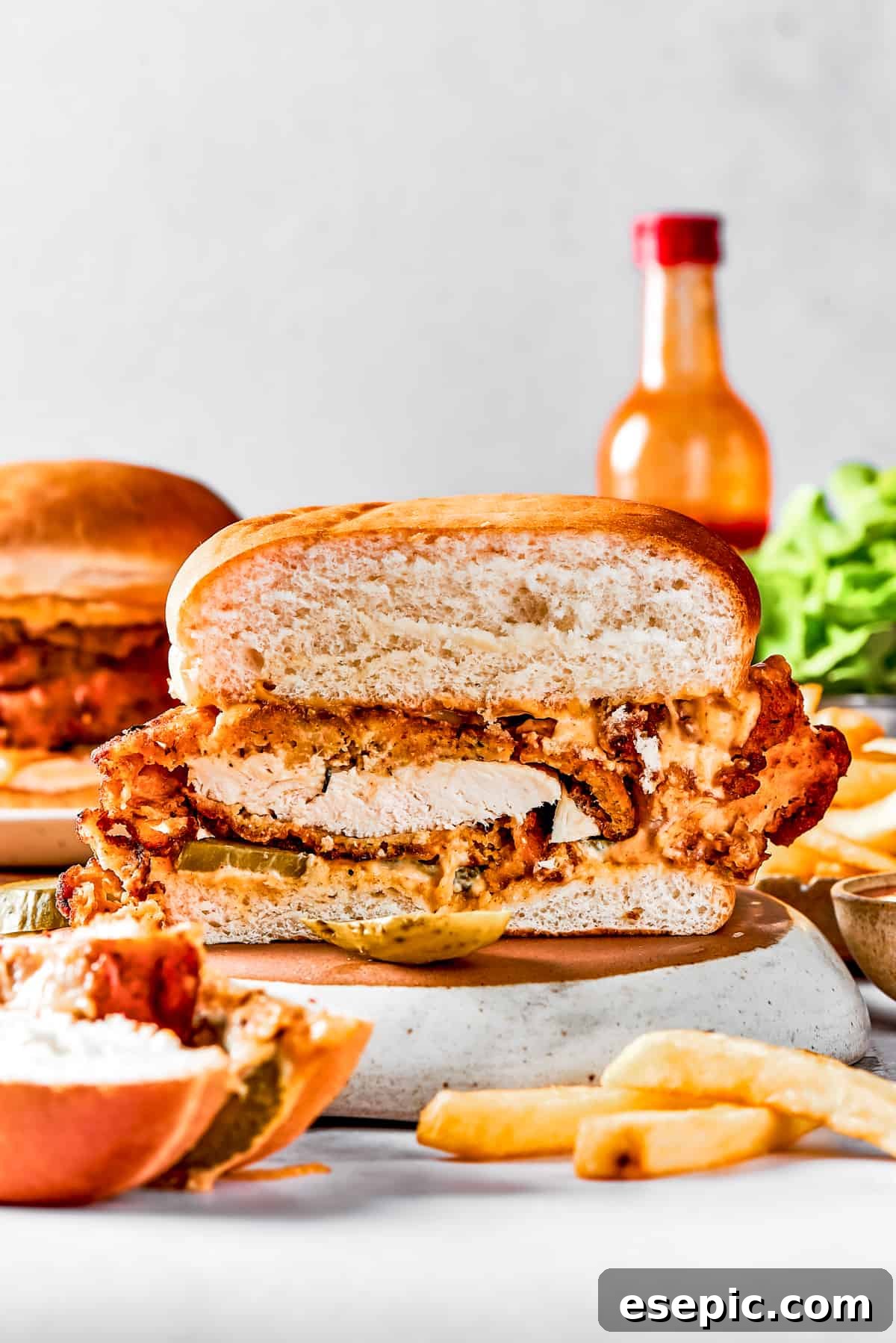 Homemade chicken sandwich sliced in half A homemade chicken sandwich cut in half, showcasing the thick, crispy fried chicken fillet, pickles, and soft bun.
