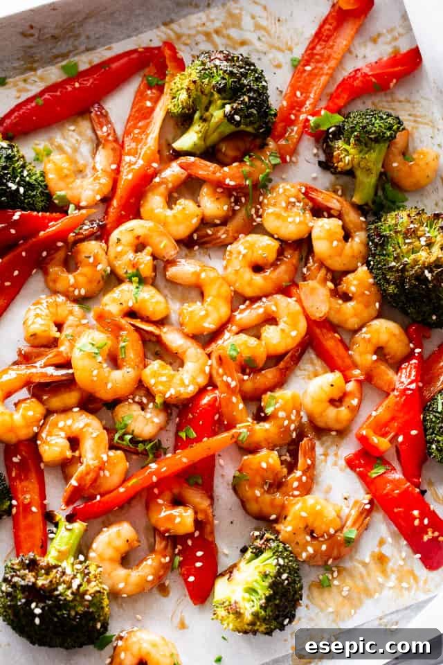 Overhead photo of a baking sheet with cooked shrimp, broccoli, and red bell peppers, freshly roasted.