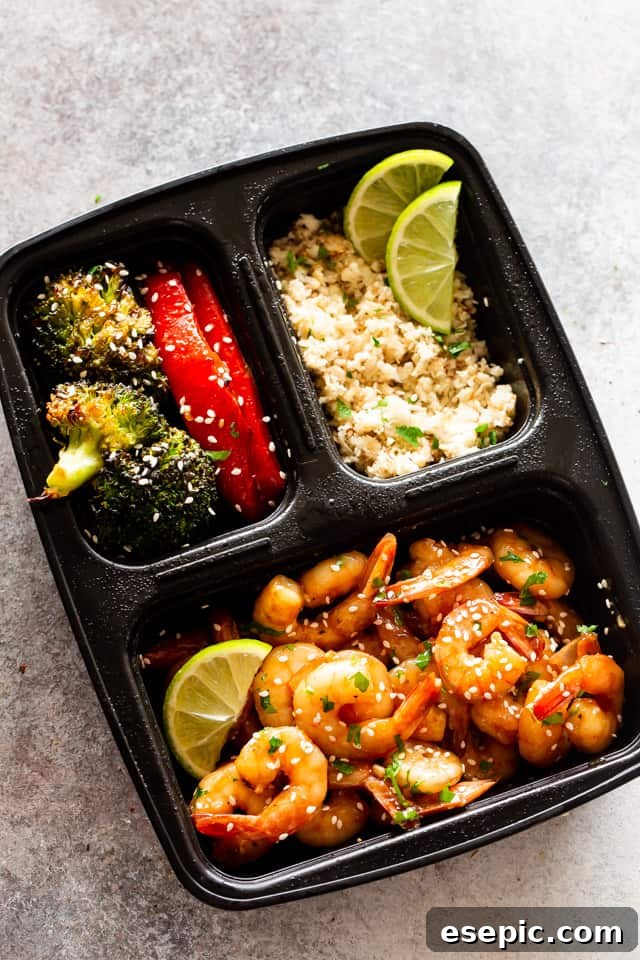 Photo of cooked shrimp, stir-fried veggies, and rice in a black container, perfect for a packed lunch.