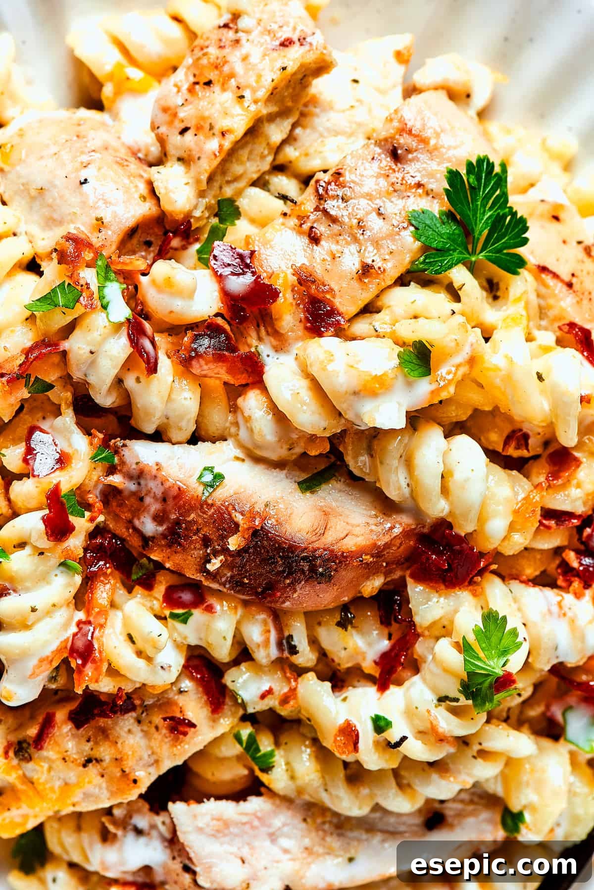 A close-up view of a serving of Chicken Bacon Ranch Pasta, elegantly garnished with fresh parsley, highlighting its rich, creamy texture and vibrant flavors.