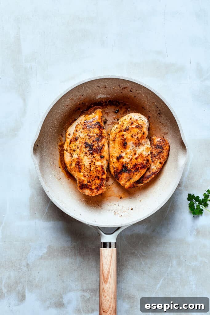 Slicing a chicken breast in half to create thinner pieces for faster cooking.